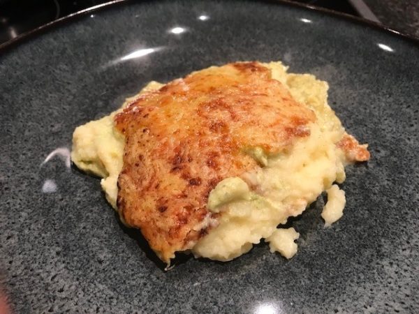 Gegratineerde ovenschotel met zalm, prei, aardappelpuree en courgette-kaassaus